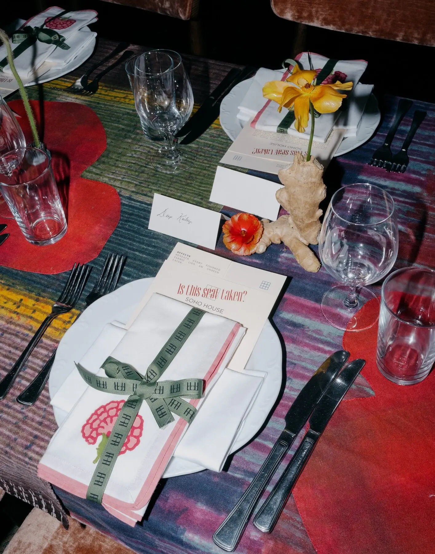 Place setting with Is This Seat Taken? menu and pink carnation napkin